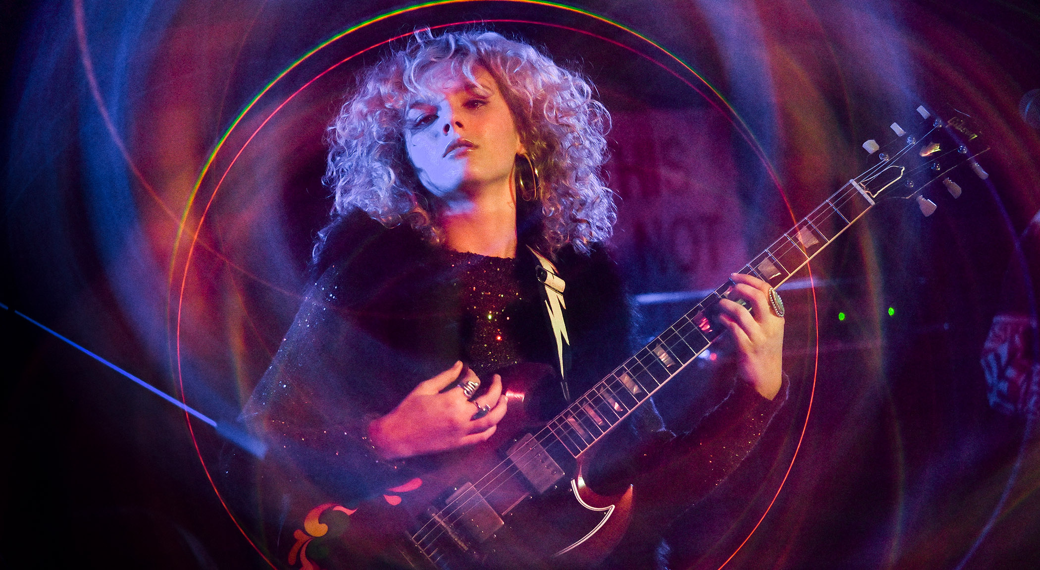 A psychedelic image of up-and-coming guitar hero Grace Bowers as she stairs into the camera and plays a barre chord on her Gibson SG